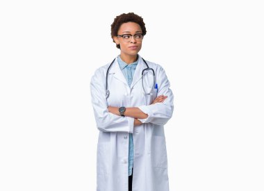 Görünümlü yan ve dik dik bakma uzağa düşünce gülümseyen izole arka plan üzerinde tıbbi ceket giyen genç Afro-Amerikan doktor kadın.