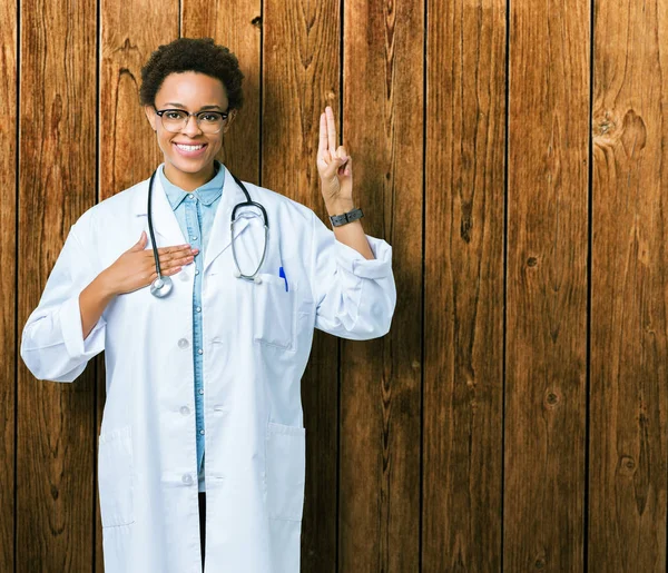 年轻的非洲医生妇女穿着医疗外套在孤立的背景用手在胸部和手指发誓 作出忠诚的承诺宣誓 — 图库照片