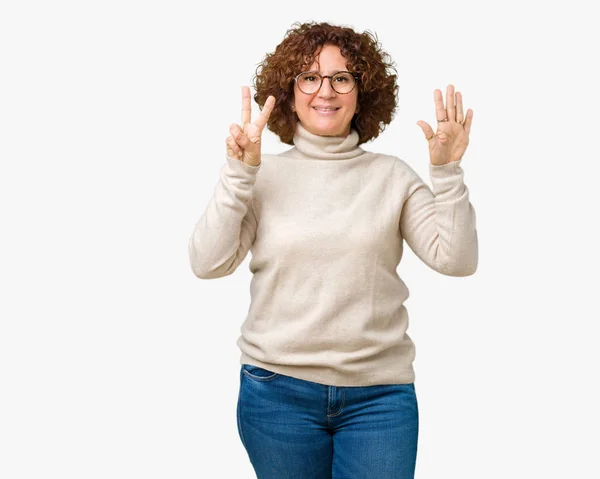 美丽的中年老年妇女穿着高领毛衣和眼镜在孤立的背景显示和手指指向数字 而微笑着自信和快乐 — 图库照片