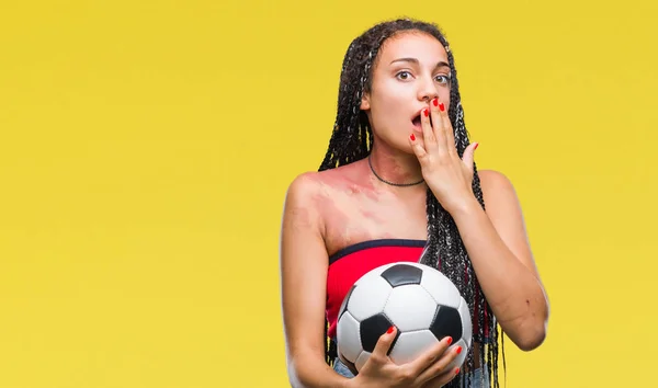 Young braided hair african american with birth mark holding soccer ball over isolated background cover mouth with hand shocked with shame for mistake, expression of fear, scared in silence, secret concept