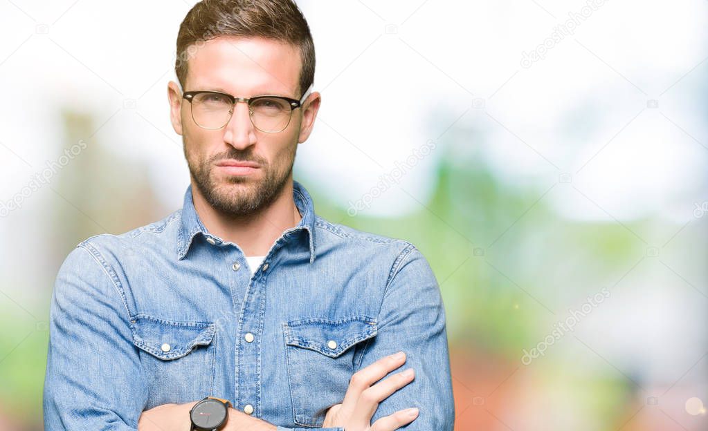 Handsome man wearing glasses skeptic and nervous, disapproving expression on face with crossed arms. Negative person.