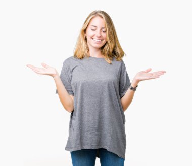 Gülen iki elle gösterilen açık avuç içi, sunma ve karşılaştırma ve denge reklam arka plan üzerinde büyük boy rahat t-shirt giyen güzel ve genç birbayan izole