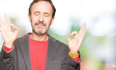 Orta yaş yakışıklı iş adamı rahatla ve gülümseyen gözlerle kapalı parmak jestle meditasyon yapıyor. Yoga kavramı.