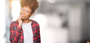 Diş ağrısı veya dişlerde dişlerle ilgili hastalık nedeniyle ağız acı ifadesi ile el ile dokunmak izole arka plan üzerinde gözlük güzel genç Afro-Amerikan kadın. Diş hekimi kavramı.