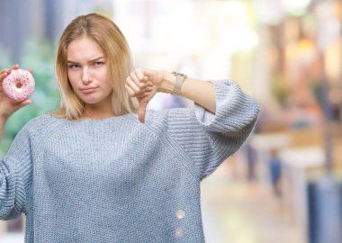 Kızgın yüz, eksi işareti aşağı antipati başparmak ile gösterilen, ret kavramı ile izole arka plan üzerinde tatlı çörek yiyen genç kafkas kadın