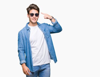 Genç yakışıklı adam giyen güneş gözlüğü izole üzerinde bir parmak, harika bir fikir ya da düşünce, iyi hafıza ile baş gösteren gülen arka plan