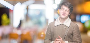 Arka plan eller üzerinde kış ceket giyen genç yakışıklı adam birlikte izole ve rahat ve neşeli gülümseyen parmak çarpı işareti. Başarı ve iyimser