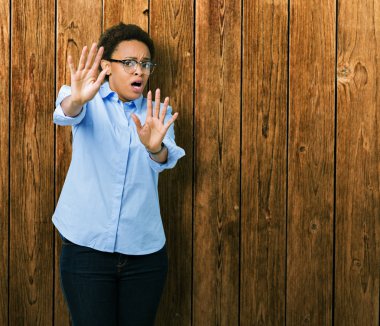 İzole arka plan üzerinde genç güzel Afrikalı Amerikan iş kadını korkuyor ve korku ifadesi ile korkuyor el ile hareket durdurmak, şok bağırıyor. Panik konsepti.