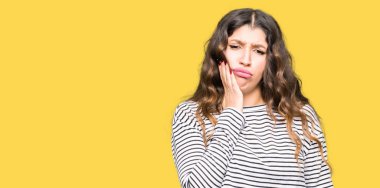 Diş ağrısı veya dişlerde dişlerle ilgili hastalık nedeniyle ağız acı ifadesi ile el ile dokunmak çizgili Süveter giyen genç güzel kadın. Diş hekimi kavramı.