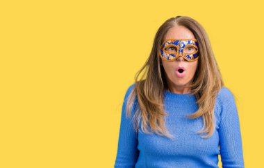 Güzel orta yaş kadın giyiyor Venedik karnaval maskesi korkuyor ve şok sürpriz ifade ile izole arka plan üzerinde korku ve yüz heyecanlı.