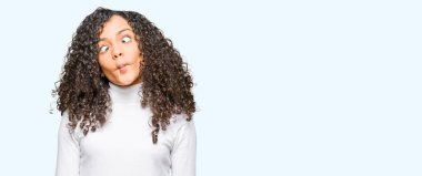 Kıvırcık saçlı Balıkçı Yaka Kazak dudaklı, çılgın ve komik bir jest yapma balık yüz giyen genç güzel kadın. Komik ifade.