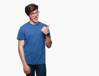 Seyir ve başparmak yanında yukarıyı mutlu yüz ile gülümseyen izole arka plan üzerinde gözlük takan genç yakışıklı adam.