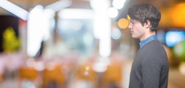 Genç yakışıklı zarif adam izole arka tarafına, seyir üzerinde dinlenmek doğal yüz emin gülümseme ile pozuyla profil.