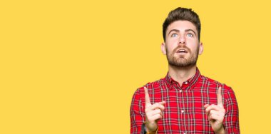 Genç yakışıklı adam şaşırdı ve şaşırdı. Parmaklarıyla işaret etti ve kollarını kaldırdı..