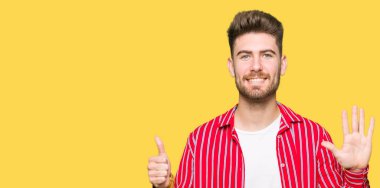 Gösterilen ve parmakları ile işaret kırmızı gömlek giymiş genç yakışıklı adam kendinden emin ve mutlu gülümseyerek süre 6 numara.