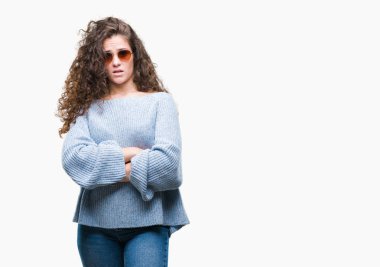 Güzel esmer kıvırcık saçlı Genç kız izole arka plan şüpheci ve sinir, onaylamayan ifade yüz çapraz kolları üzerinde güneş gözlüğü takıyor. Negatif kişi.