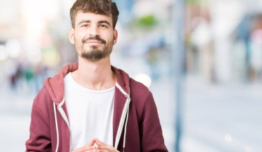 Genç yakışıklı adam arka plan eller birlikte izole ve rahat ve neşeli gülümseyen parmak çarpı işareti. Başarı ve iyimser