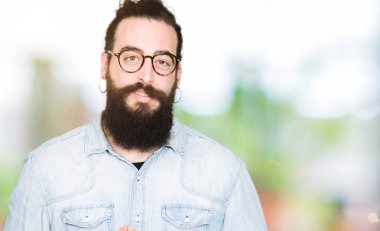 Genç hipster adam uzun saçlı ve gözlüklü eller birlikte sakal ve parmakları ile rahat ve neşeli gülümseyen geçti. Başarı ve iyimser