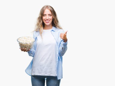 Ok işareti, başparmak ile parmak, mükemmel işareti yapıyor kocaman bir gülümseme ile izole arka plan üzerinde mutlu patlamış mısır yemek güzel sarışın genç kadın