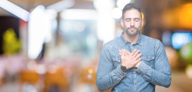 Yakışıklı delikanlı ile gülümseyen izole arka plan üzerinde kapalı gözler ve yüzünde minnettar jest ile göğüs üzerinde eller. Sağlık kavramı.