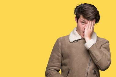 Yakışıklı delikanlı üzerinde kış palto giyiyor yarım yüz, göz ve ağız el ile kapsayan Yawning yorgun arka plan izole. Acı yüzü acıyor.