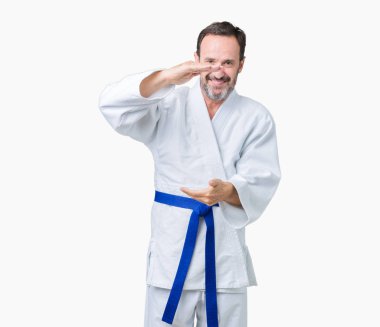 Yakışıklı orta yaş komuta sizde kimono üniforması üzerinde arka plan ile büyük ve büyük boy işaret, ölçü birimi sembol gösteren el eller izole. Kameraya bakarak gülümsüyordu. Ölçüm kavramı.