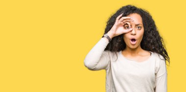 Kıvırcık saç ile genç güzel kız rahat kazak yaparken Sürpriz yüz ile şok ok jest yapıyor, göz parmaklar bakarak. İnanılmaz ifade.