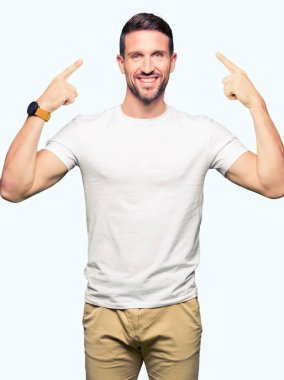 Yakışıklı adam rahat beyaz t-shirt gülen her ikisi ile baş gösteren giyen eller parmak, harika bir fikir ya da düşünce, iyi hafıza