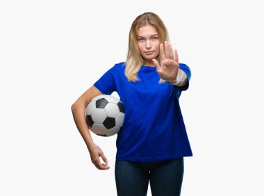 Açık eliyle dur işareti ile ciddi ve kendine güvenen ifade, savunma jest yapıyor izole arka plan üzerinde futbol topu tutan genç beyaz kadın