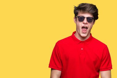 Yakışıklı delikanlı korkuyor ve şok sürpriz ifade, korku ve heyecan yüz ile izole arka plan üzerinde güneş gözlüğü takıyor.
