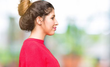 Kırmızı kazak ve çörek tarafına, seyir giyen genç güzel kadın dinlenmek doğal yüz emin gülümseme ile pozuyla profili.