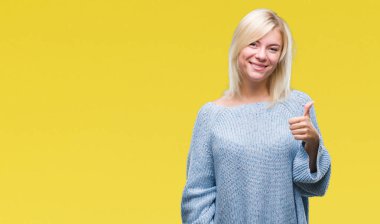 Hareketi el ile mutlu yaşasın yapıyor izole arka plan üzerinde kış kazak giyen genç güzel sarışın kadın. Kameraya bakarak başarı gösteren ile ifade onaylama.