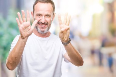 Orta yaş ağarmış komuta sizde gösterilen ve parmakları ile işaret izole arka plan üzerinde beyaz t-shirt giyen kendinden emin ve mutlu gülümseyerek süre sekiz numara.