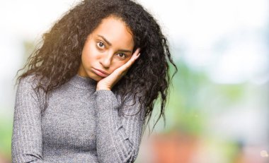 Kıvırcık saçlı düşünme görünümlü genç güzel kız yorgun ve sıkılmış çapraz silah depresyon sorunları ile.