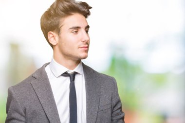 Genç iş adamı elbise giyiyor ve izole arka plan üzerine kravat yüzüne gülümseme ile yan bakıyor, doğal ifade. Güven gülüyor.