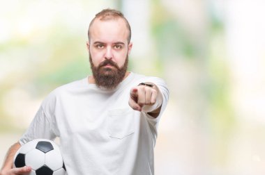Genç beyaz hipster adam futbol futbol topu tutan kamera ve size parmak ile işaret arka plan izole, el işareti, pozitif ve kendinden emin bir jest ön