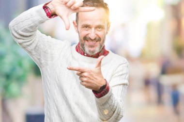 Elle yapma çerçeve ve parmakları ile mutlu yüz gülümseyen izole arka plan üzerinde kış kazak giyen orta yaş ağarmış komuta sizde. Yaratıcılık ve Fotoğrafçılık kavramı.