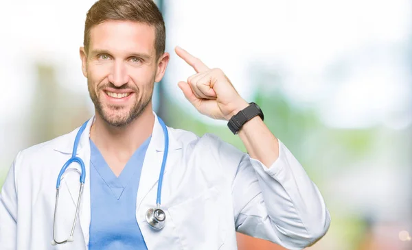英俊的医生穿医疗制服在孤立的背景微笑用一个手指指向头部 伟大的想法或想法 良好的记忆力 — 图库照片