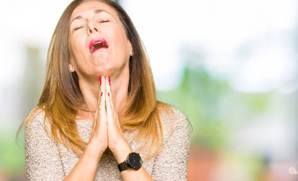 Beautiful middle age woman wearing fashion sweater begging and praying with hands together with hope expression on face very emotional and worried. Asking for forgiveness. Religion concept.