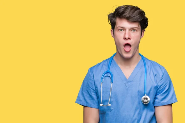 驚きの表現 恐怖と興奮した顔でショックを受けて孤立した背景に医療制服を着て若い医者 — ストック写真