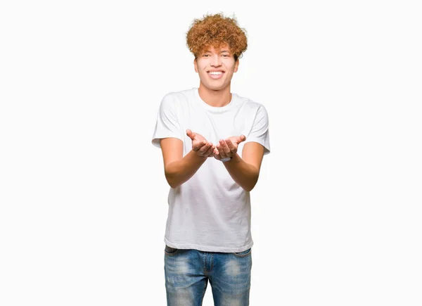 年轻英俊的男子与非洲头发穿着休闲白色 T恤微笑与手手掌一起接受或给予手势 保持和保护 — 图库照片