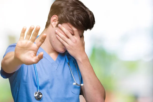 年轻的医生穿着医疗制服在孤立的背景覆盖眼睛用手和做停止手势与悲伤和恐惧的表情 尴尬和消极的概念 — 图库照片