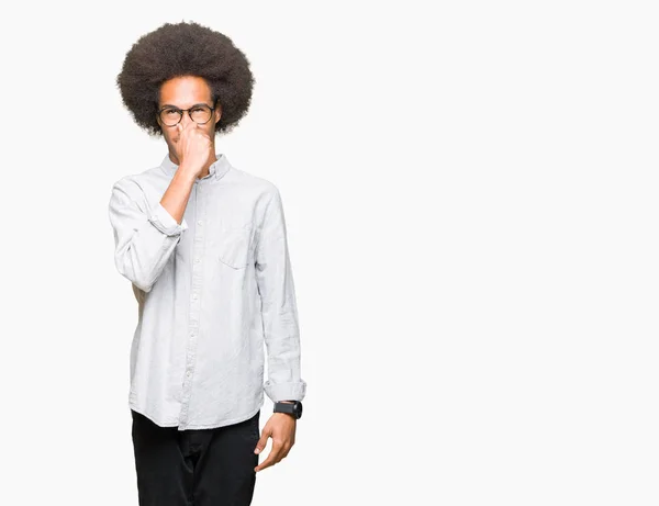 非洲青年美国男子戴着非洲头发 戴着眼镜 闻到了臭味 难闻的气味 用手指在鼻子上屏住呼吸 难闻的气味概念 — 图库照片