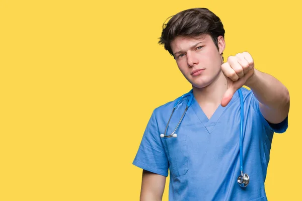 年轻的医生穿着医疗制服在孤立的背景看起来不开心和愤怒 表现出拒绝和消极的大拇指向下的姿态 错误的表达 — 图库照片