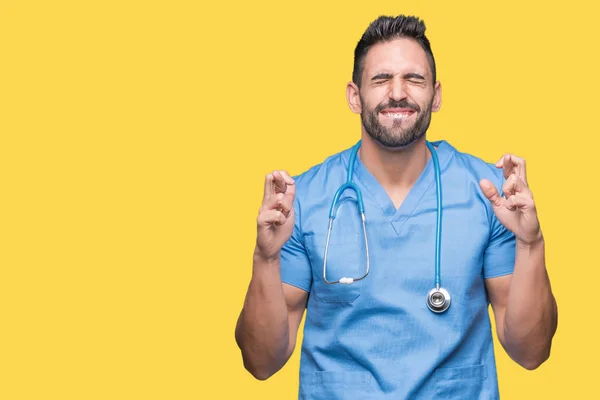 Knappe Jonge Dokter Chirurg Man Geïsoleerde Achtergrond Glimlachend Kruising Vingers — Stockfoto