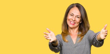 Güzel orta yaş iş kadını sarılmak için açık kollar ile gülümseyen kamera bakıyor. Mutluluğu kucaklayan neşeli ifade.