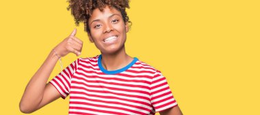 Güzel genç Afro-Amerikan kadın yapıyor gülümseyen izole arka plan üzerinde telefon hareketi ile el ve parmak telefonda konuşuyor gibi. Kavramları iletişim.