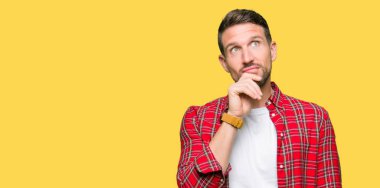 Çene düşünme hakkında soru, dalgın ifade üzerine el ile rahat gömlek giymiş yakışıklı adam. Düşünceli yüzüyle gülümsüyor. Şüphe kavramı.