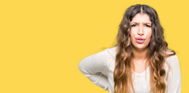 Beyaz kazak giyen genç güzel kadın sırt ağrısı, el ile geri, kas ağrısı dokunmadan, acı