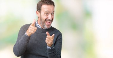 Yakışıklı orta yaş üst düzey fotoğraf makinesi ile mutlu ve komik yüz için parmakları işaret izole arka plan üzerinde bir kazak giyen adam. İyi enerji ve vibes.